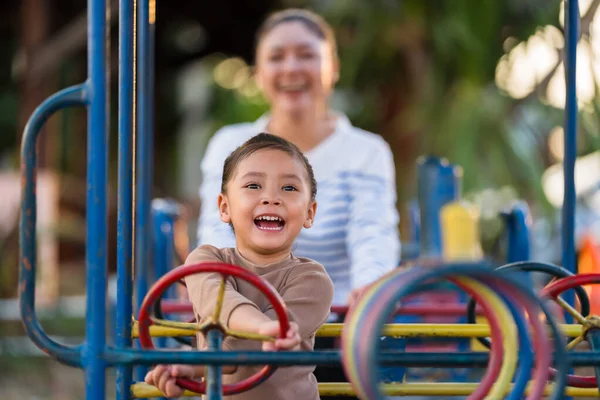 Çocuk kız annesiyle oyun parkında direksiyon oyuncağıyla oynuyor.