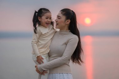 Sevgi dolu bir anne gün batımını izlerken çocuğunu kucağına alır.