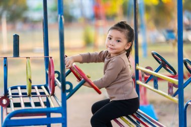 Çocuk kız oyun parkında direksiyon oyuncağıyla oynuyor.