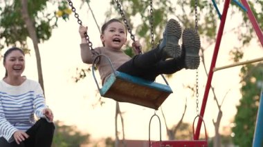 Annesiyle birlikte çocuk parkında salıncakta sallanan neşeli kızın ağır çekimleri.