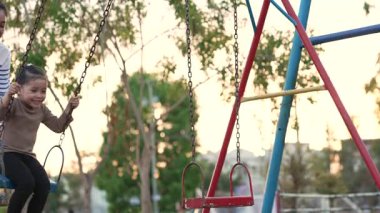 Annesiyle birlikte çocuk parkında salıncakta sallanan neşeli kızın ağır çekimleri.