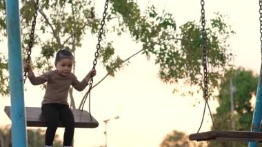Çocuk parkında salıncakta sallanan neşeli kızın yavaş çekimleri.
