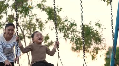 Annesiyle birlikte çocuk parkında salıncakta sallanan neşeli kızın ağır çekimleri.