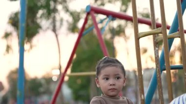 Annesiyle açık hava çocuk parkında çifte salıncakta oynayan neşeli kızın ağır çekimleri.