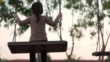 Çocuk parkında salıncakta sallanan neşeli kızın yavaş çekimleri.