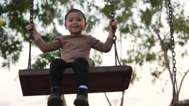 Çocuk parkında salıncakta sallanan neşeli kızın yavaş çekimleri.