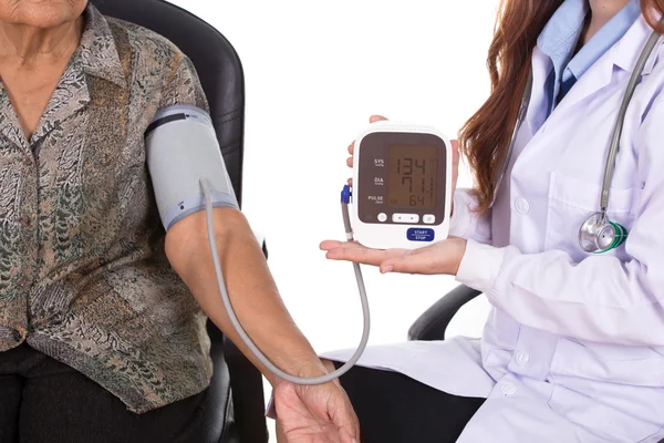 Female doctor measuring blood pressure of senior woman — Stock Photo, Image