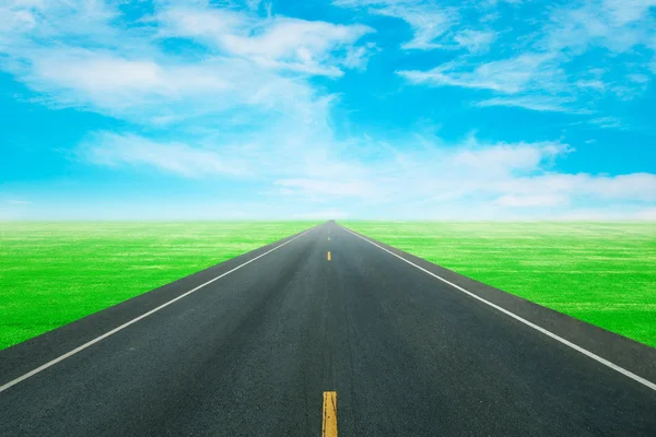 Асфальтовая дорога через зеленое поле — стоковое фото