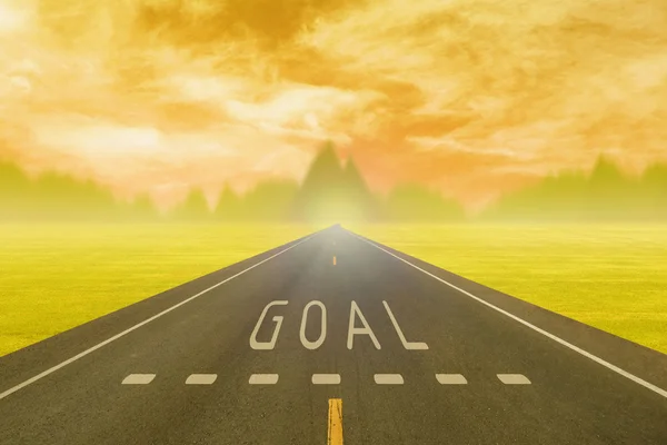Road through the field with sign goal on asphalt at sunset — Stock Photo, Image