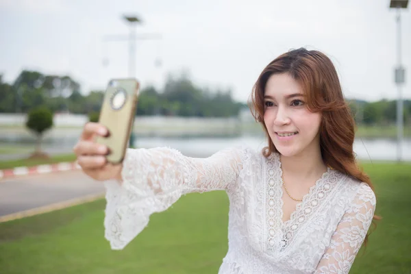 Bella giovane donna selfie nel parco con uno smartphone — Foto Stock