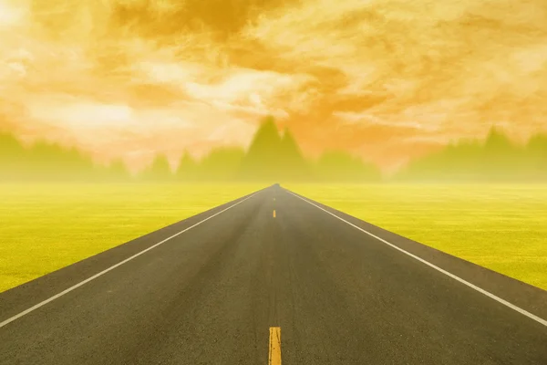 Asfaltová silnice přes pole při západu slunce — Stock fotografie