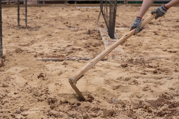 Cavando el suelo con una azada en la construcción — Foto de Stock