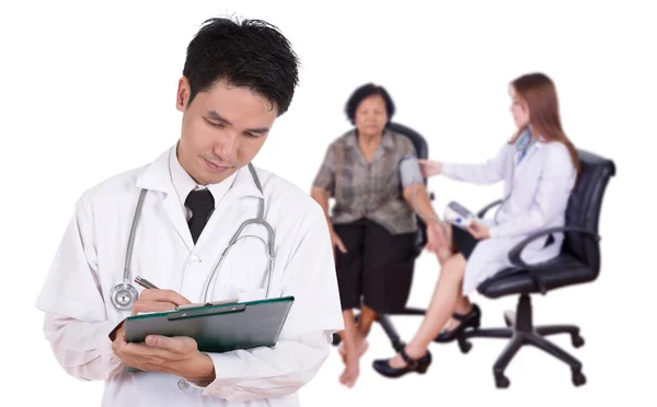 Doctor writting medical report with female doctor measuring bloo — Stock Photo, Image