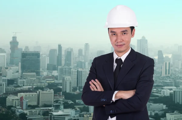 工程师在头盔双臂交叉，城市的背景下 — 图库照片
