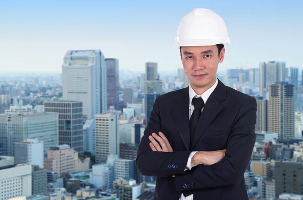 Ingenieur im Helm mit verschränkten Armen, Hintergrund der Stadt — Stockfoto