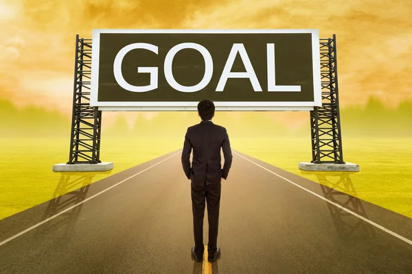 Businessman standing on road and looking with large sign of goal — Stock Photo, Image