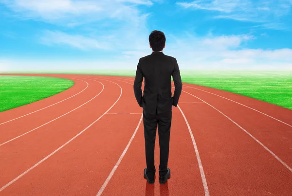 Businessman standing on running track and looking to goal Stock Image