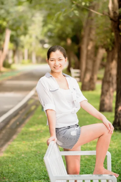 Jovem mulher asiática relaxante ao ar livre olhando feliz e sorrindo — Fotografia de Stock