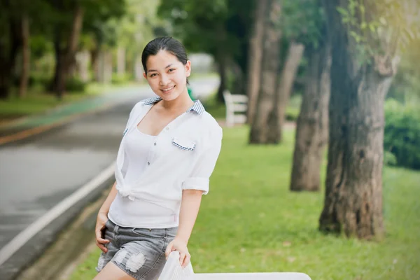 Junge asiatische Frau entspannt sich im Freien und sieht glücklich und lächelnd aus — Stockfoto