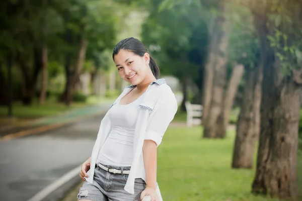 Junge asiatische Frau entspannt sich im Freien und sieht glücklich und lächelnd aus — Stockfoto