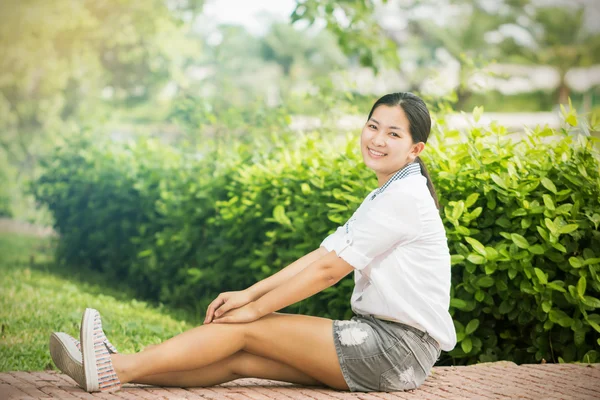 Junge asiatische Frau entspannt sich im Freien und sieht glücklich und lächelnd aus — Stockfoto
