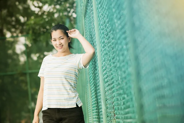 Asiatisk kvinna slappna av och smile stående på tennisbanan — Stockfoto