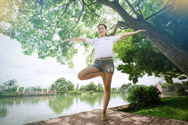 Genç Asyalı kadın dışarıda dinleniyor ve yoga yapıyor. Mutlu görünüyor ve gülümsüyor. — Stok fotoğraf