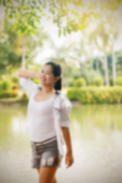 Desenfoque efecto de joven asiático mujer relajante al aire libre buscando feliz y sonriente — Foto de Stock