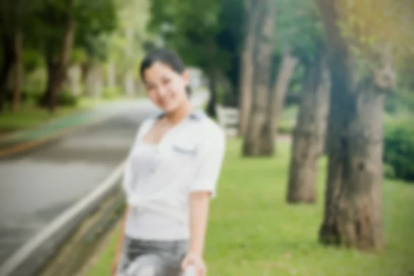 Verwischungseffekt einer jungen asiatischen Frau, die sich im Freien entspannt und glücklich und lächelnd aussieht — Stockfoto