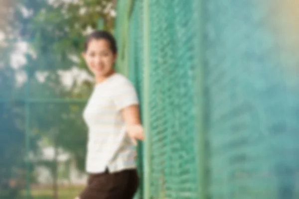 Suddig effekt av asiatisk kvinna slappna av och leende stående på tennisbana och titta på kamera — Stockfoto