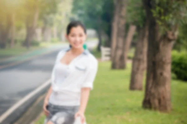 Blur effekt av ung asiatisk kvinna avkopplande utomhus ser glad och leende — Stockfoto