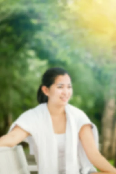 Açık havada dinlenen genç Asyalı kadının bulanıklık etkisi mutlu ve gülümsüyor — Stok fotoğraf