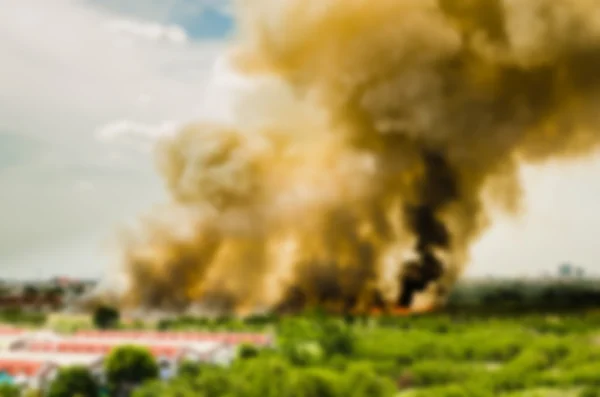 Blur hatása erdőtüzek a városban, ami egy nagy láng és füst a levegőben nagyon forró nap. Tűzoltók rohanás segít megelőzni a tűz terjedését a falu — Stock Fotó