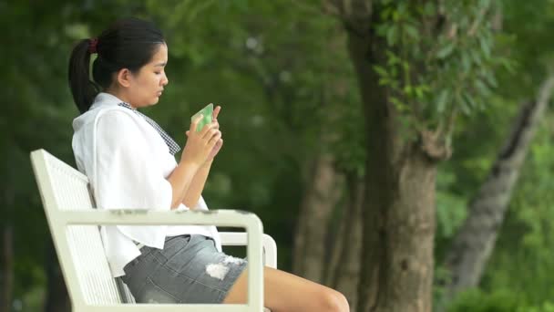 Mladá asijská žena pomocí chytrého telefonu a podívej jako relaxaci v venku hledají a: Full Hd — Stock video