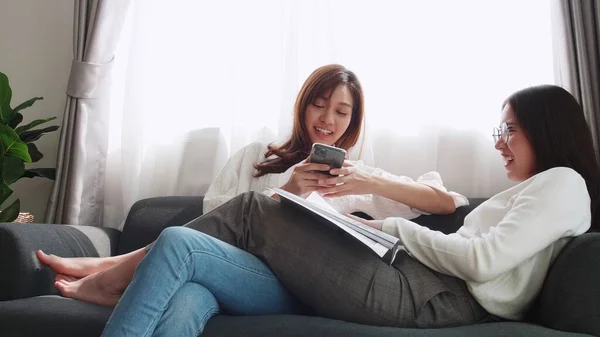 Adorável Casal Asiático Deitado Sofá Jogar Smartphone Com Amigo Sentado — Fotografia de Stock