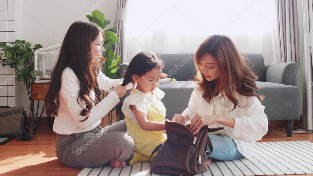 Preschool daughter excited to go to school in the first time her help packing bag. Family Couple mother and adoptive is packing a bag for her daughter to prepare for school on the first school day.