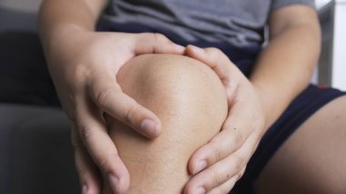 Sürekli ağrıdan muzdarip olan biri masajla ellerini dizinin üstüne koyuyor.