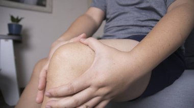 Sürekli ağrıdan muzdarip olan biri masajla ellerini dizinin üstüne koyuyor.