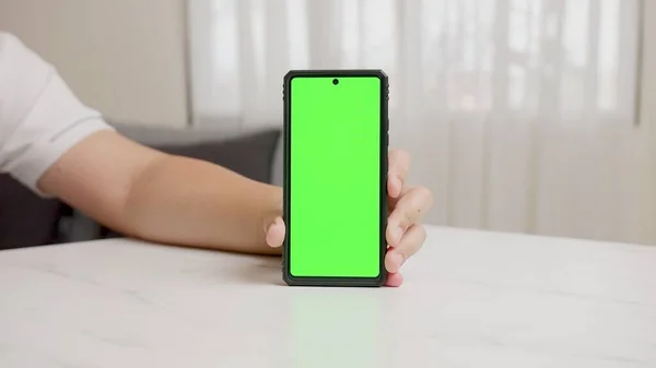 男子的手展示了具有绿色屏幕 垂直位置 与绿色背景隔离的手机 — 图库照片