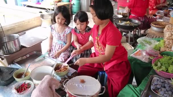 Аюттхая, Таиланд - 22 февраля 2015 года: Три девушки помогают обучать местных пекарей продавать туристам, которые путешествуют по рынку в Таиланде — стоковое видео