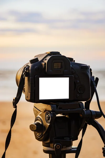 Cámara digital en la pantalla blanca aislada del trípode en la playa — Foto de Stock