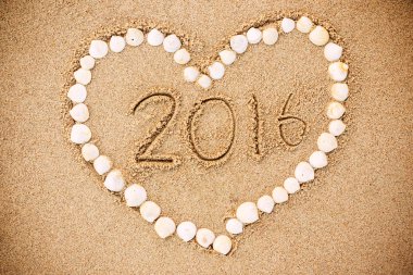 2016 inscription written in the wet yellow beach sand with Heart clipart