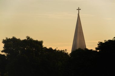 Sakin bir manzarada altın gökyüzüne bakan kilise çan kulesinin günbatımı manzarası