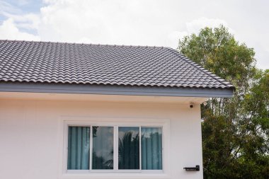 A detailed view of a modern house roof showcasing architectural elements in a serene suburban setting.