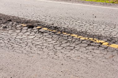 Bu resim, altyapı onarımı için hasarlı bir yol yüzeyi vurguluyor.