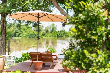 Sakin bir nehre bakan sakin bir açık hava oturma alanı dinlenmek ve doğayı takdir etmek için mükemmel..