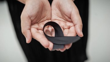 Kederi ve hatıraları simgeleyen siyah bir kurdeleyi tutan eller gibi dokunaklı bir an..