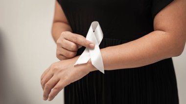 Cenaze sırasında bir kadının bileğine beyaz bir kurdele bağladığı dokunaklı bir an..