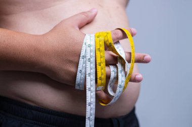 Sağlık ve zindeliği vurgulayan vücut ağırlığını ölçmek için bant bulunduran bir kişi.