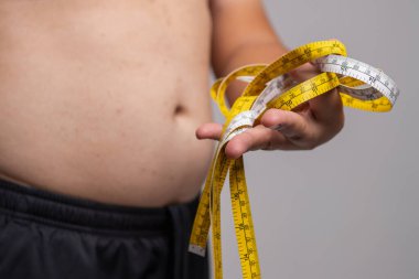 Bir insan vücudundaki yağ oranını ölçen bir mezura kullanarak sağlık durumunu tartar..